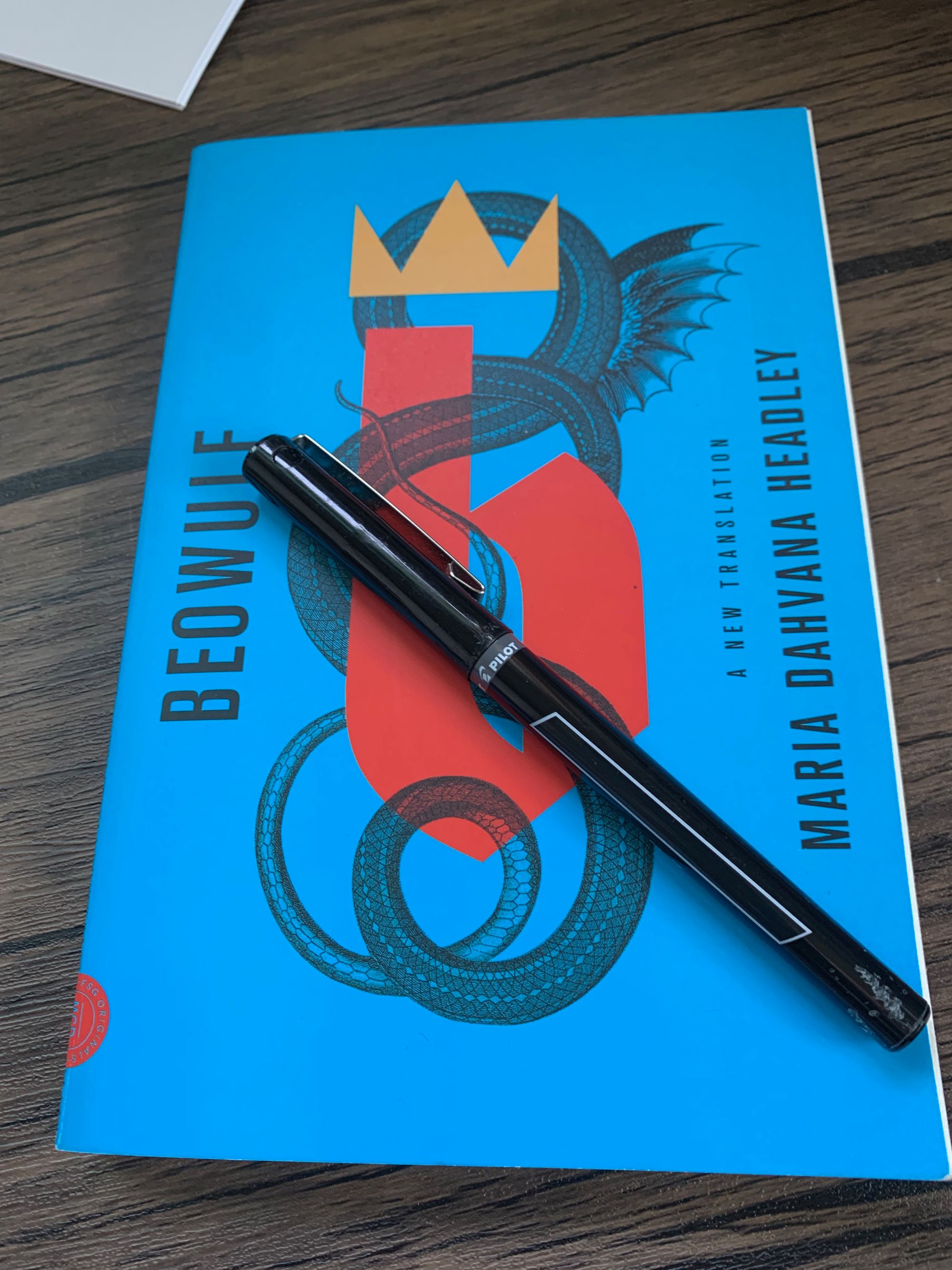 blue paperback copy of Beowulf by Maria Dahvana Headley with black pen on top