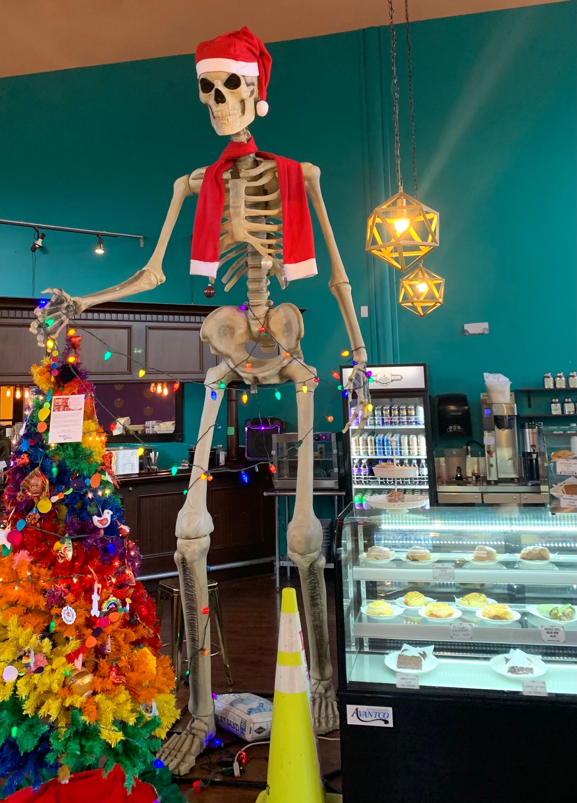 12 foot tall skeleton wearing santa hat, rainbow christmas tree, case of baked goods