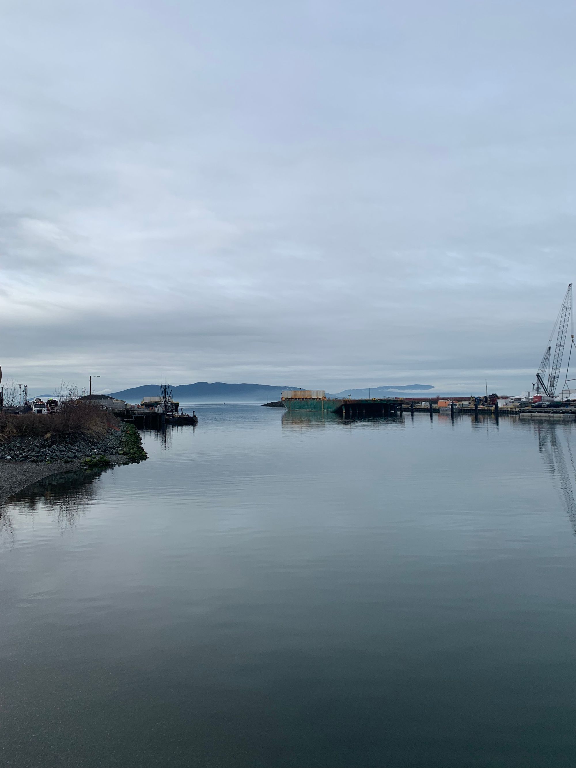 grey bay, islands in the distance, grey sky, construction equipment