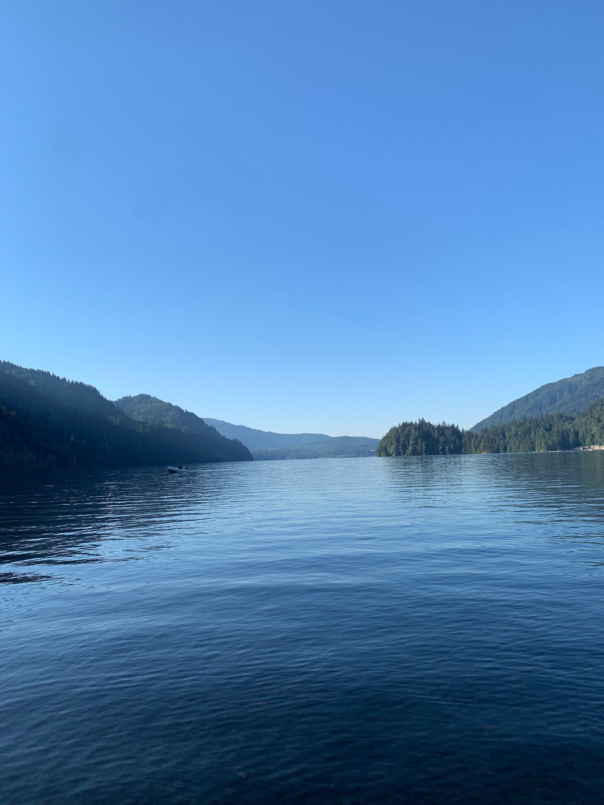 blue sky, green hills, rippling water, a small figure on a motorboat