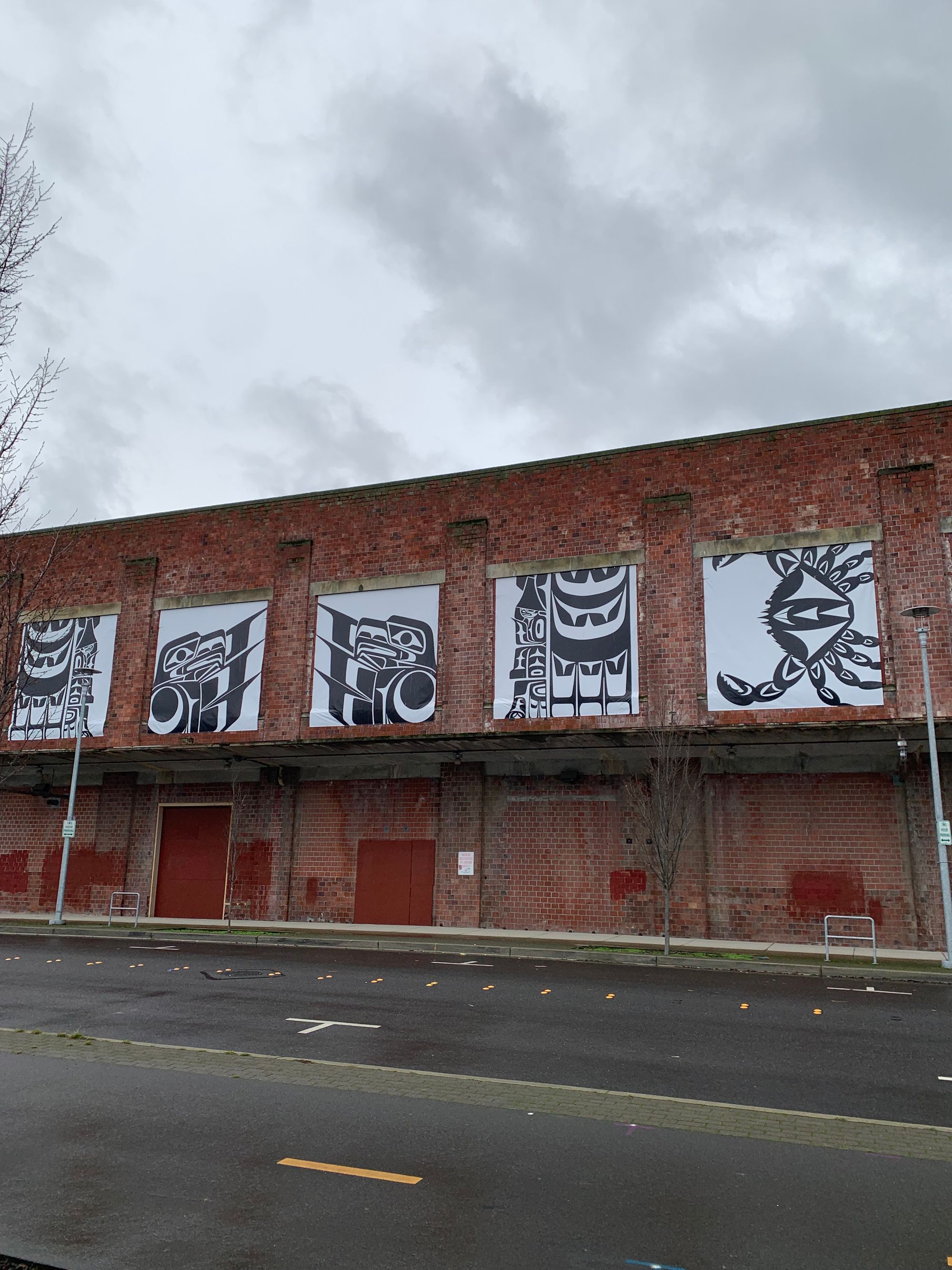 black & white graphic mural on a dilapidated brick building, grey skies above