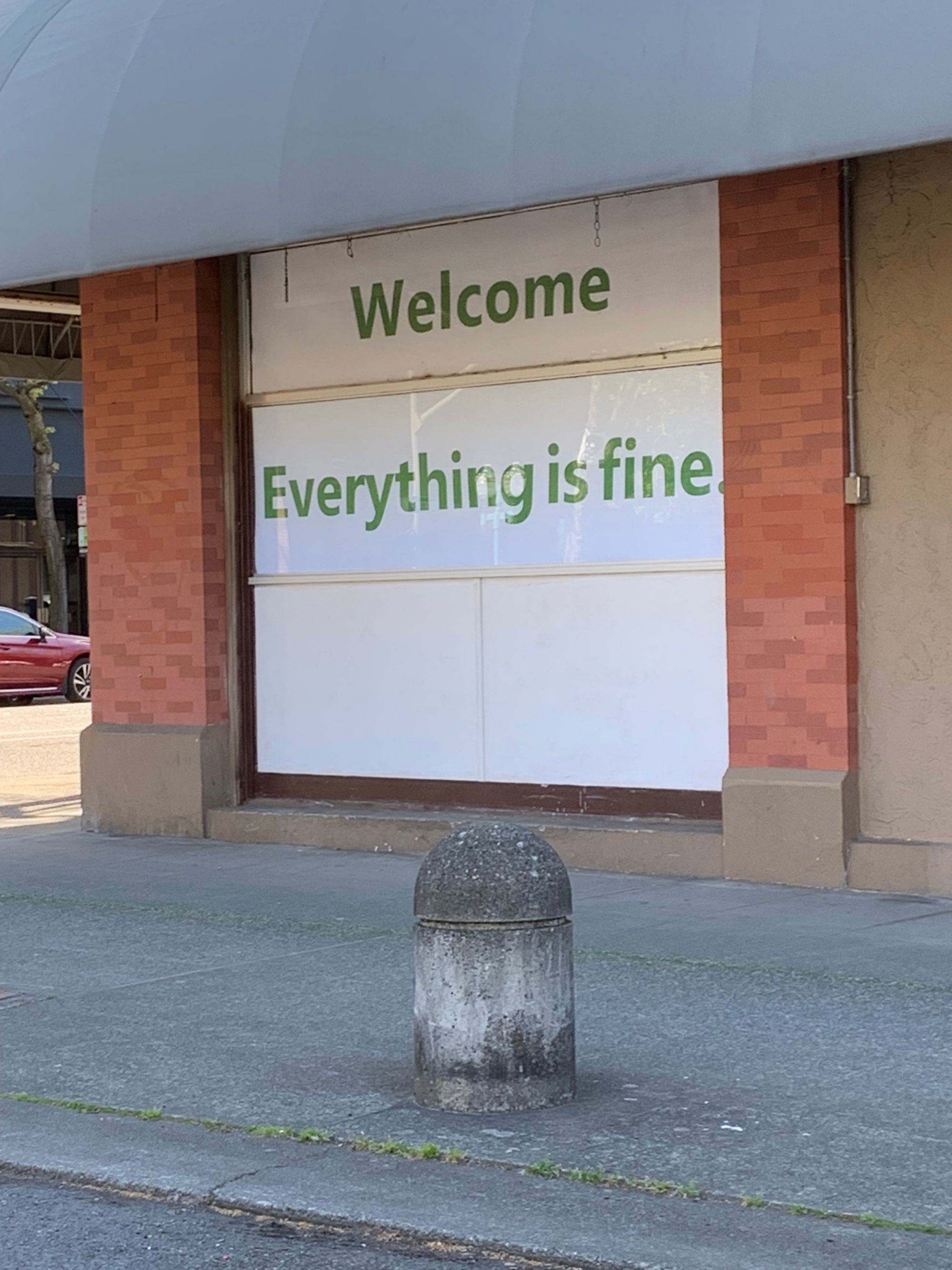 storefront window with large sign reading: Welcome. Everything is Fine. 