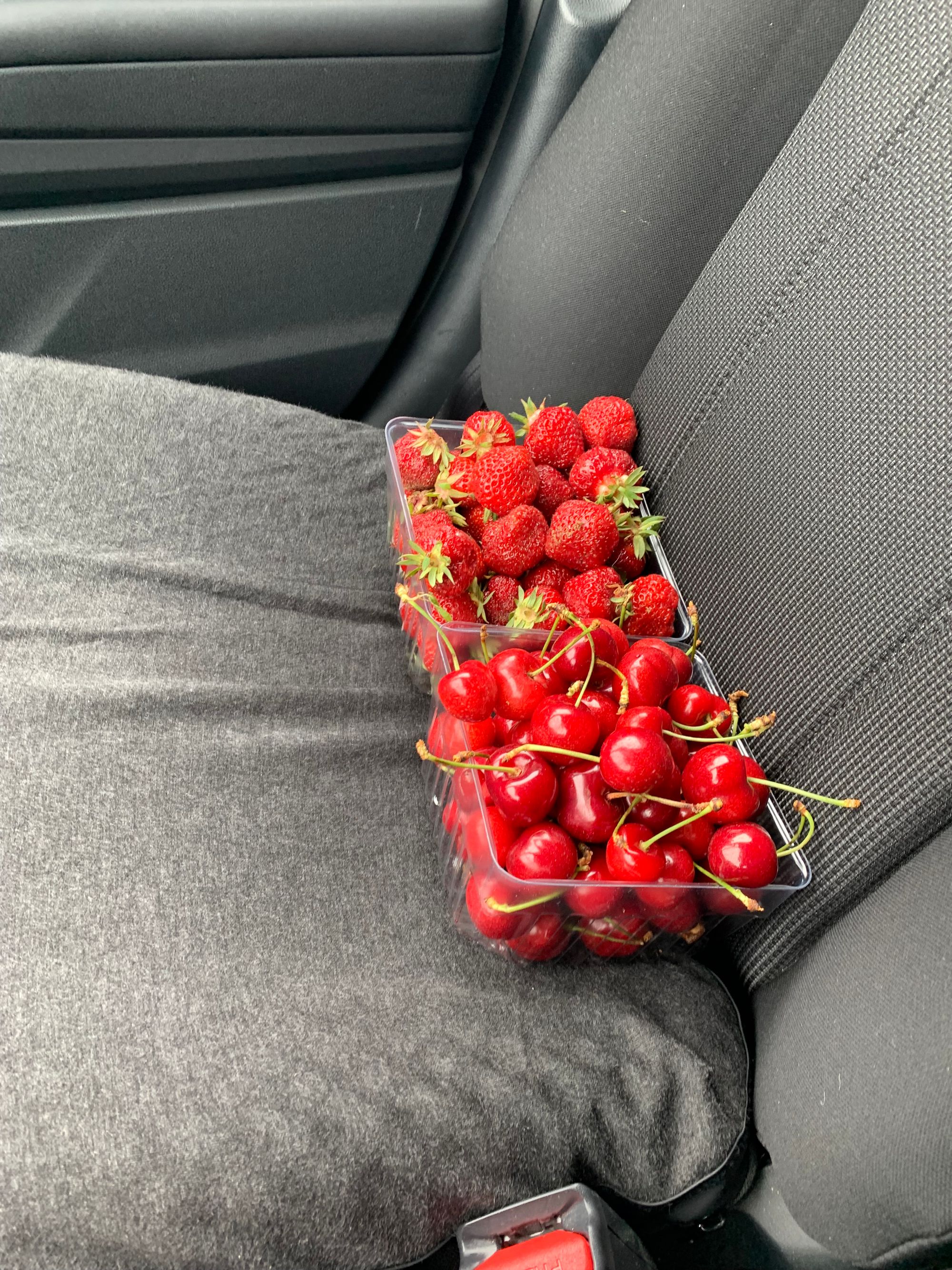 car seat with a basket of strawberries & a basket of cherries, both bright red