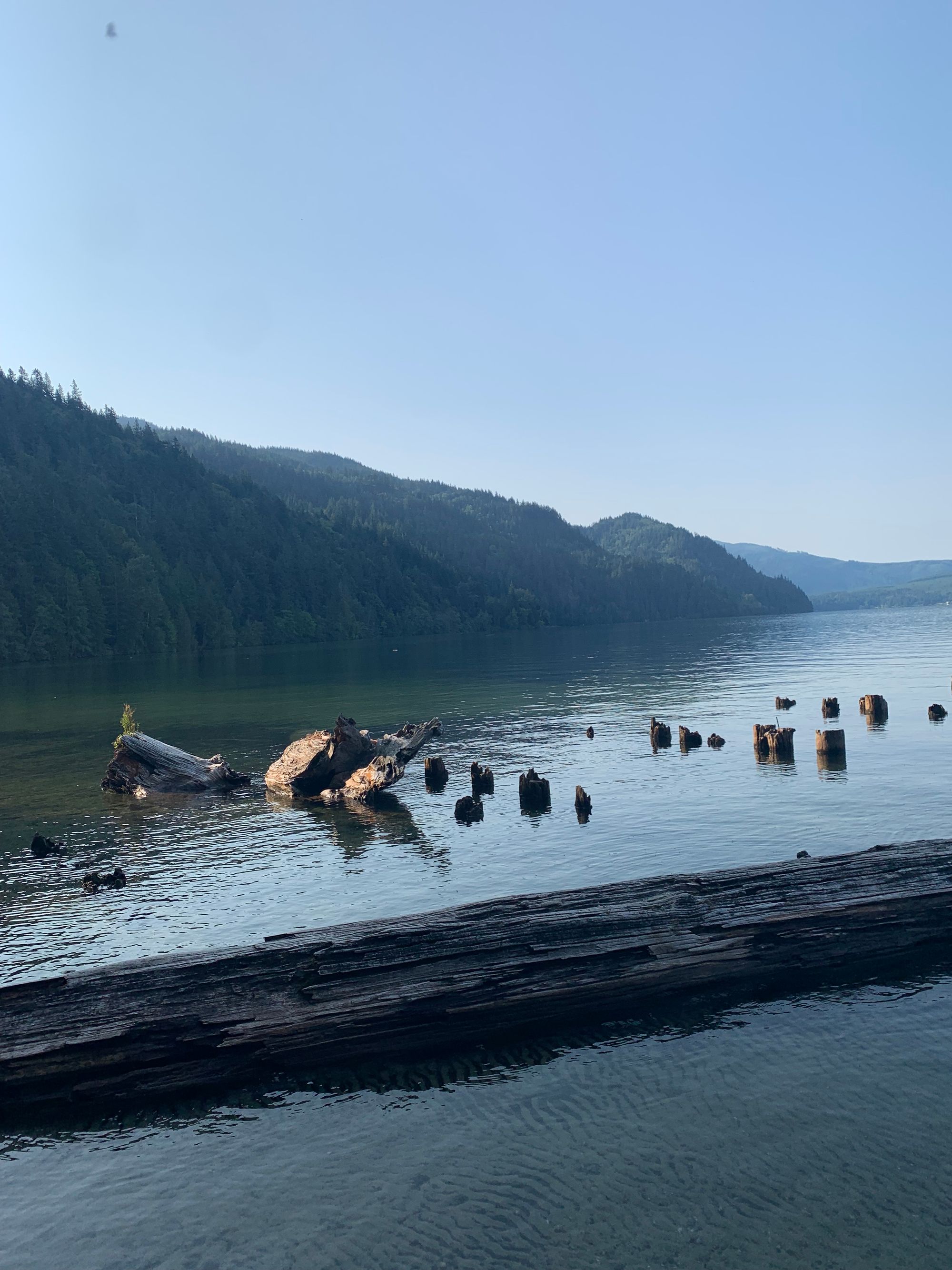 green rolling hills, a lake with the remains of a dilapidated pier, hazy blue skies