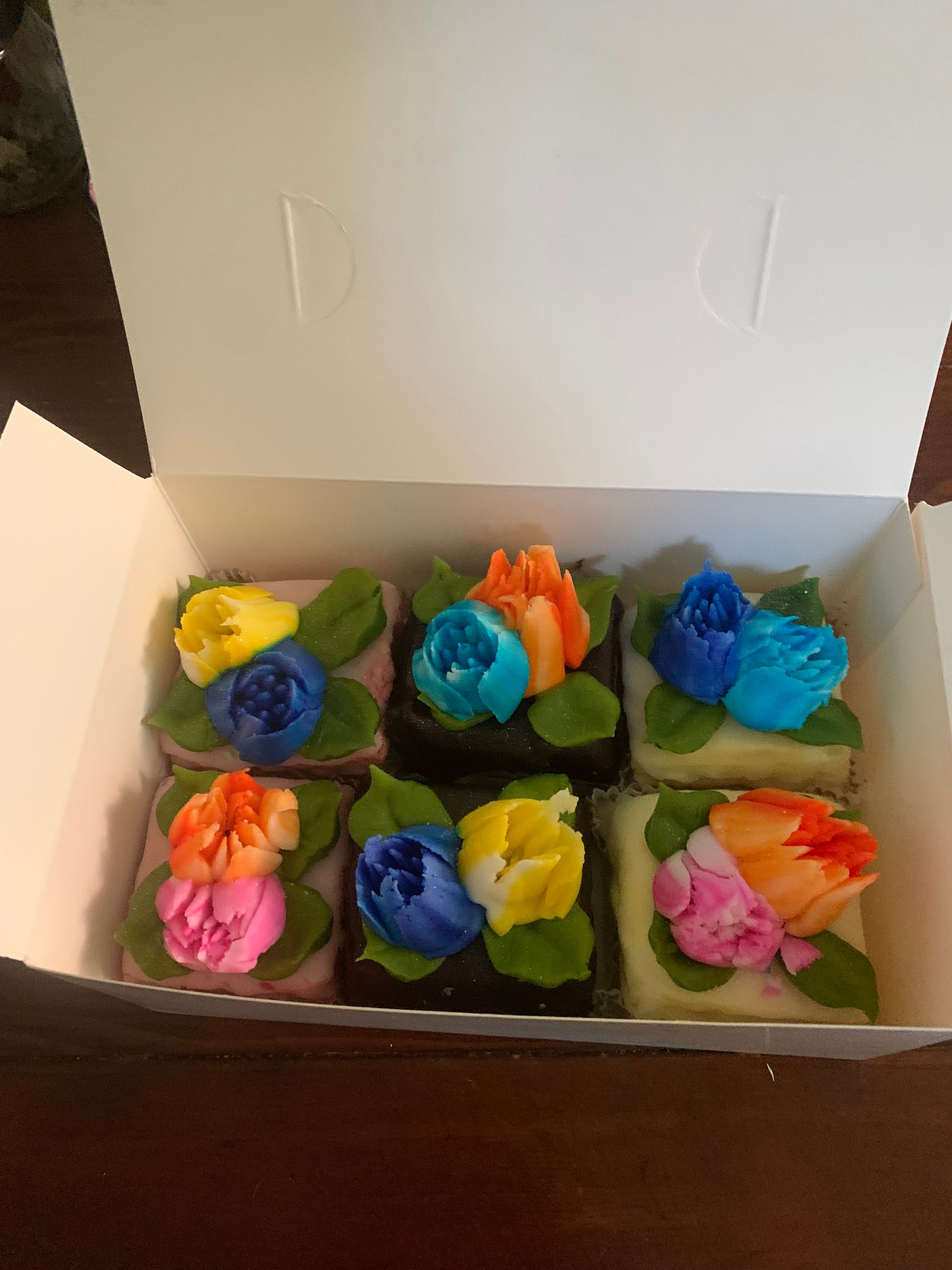 a white paper box full of colorful petit fours