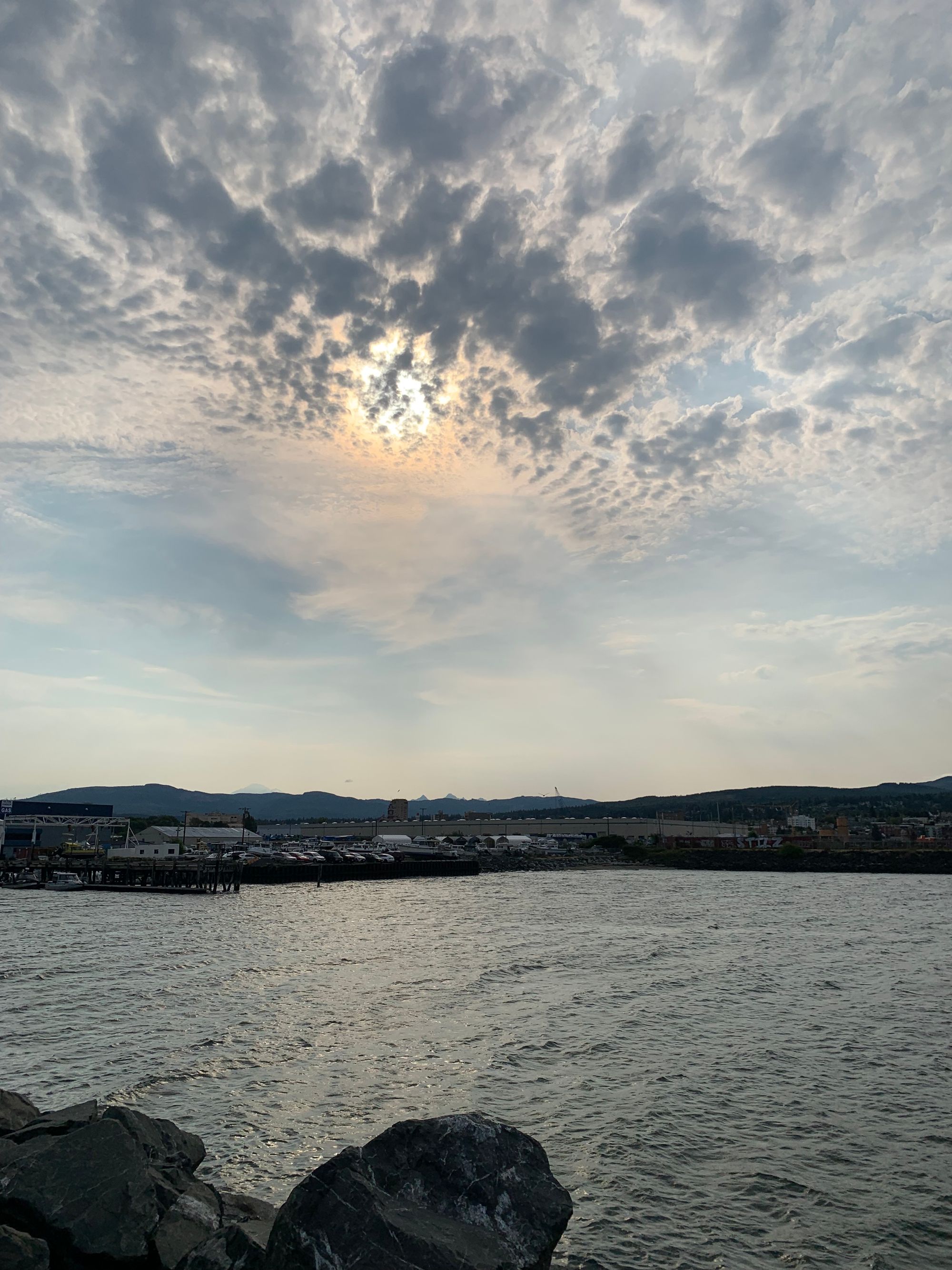 cloudy sky, silver grey water, marina, distant moutains