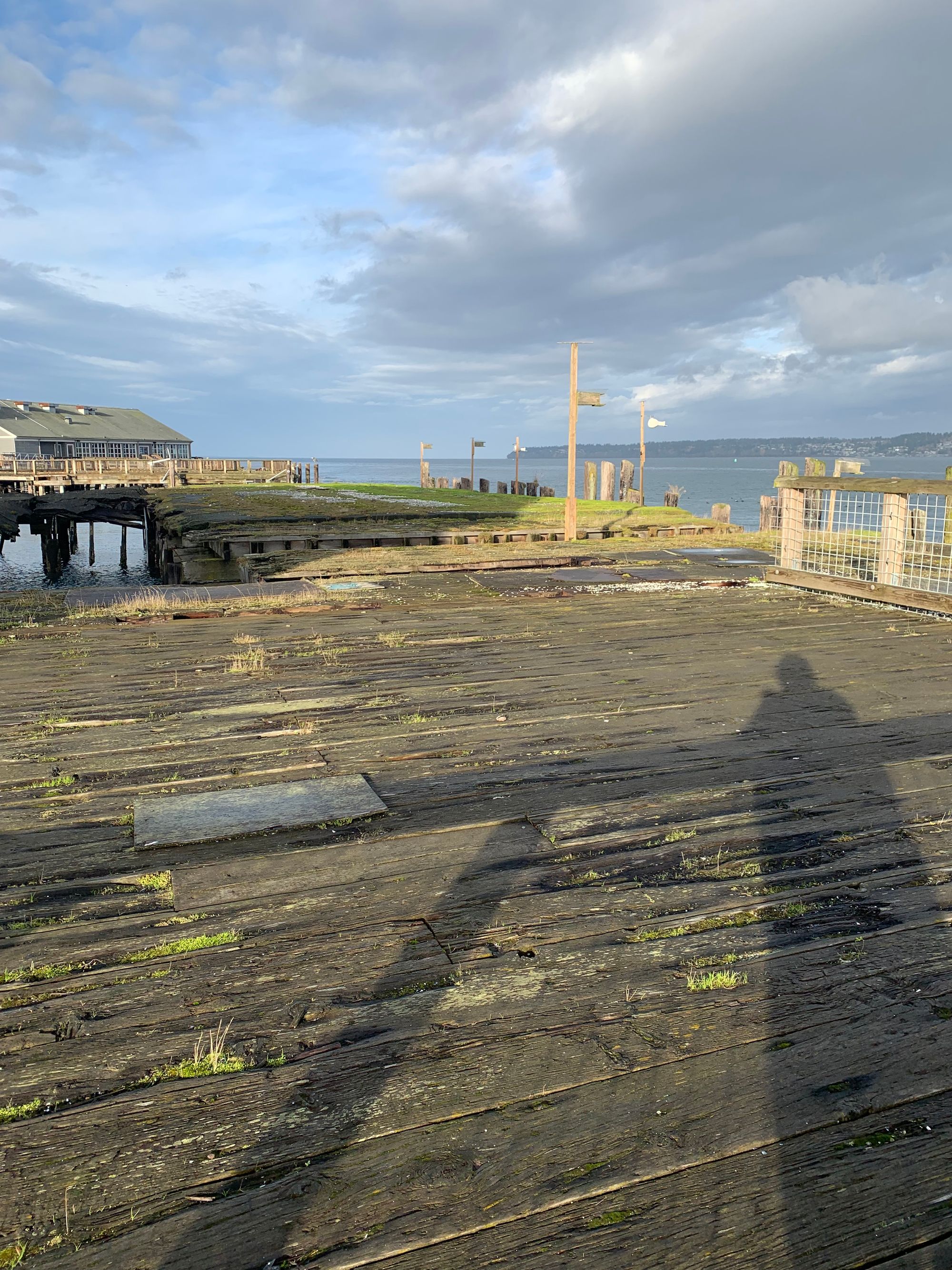 old boardwalk, shadow of the photographer, grey blue water and sky beyond