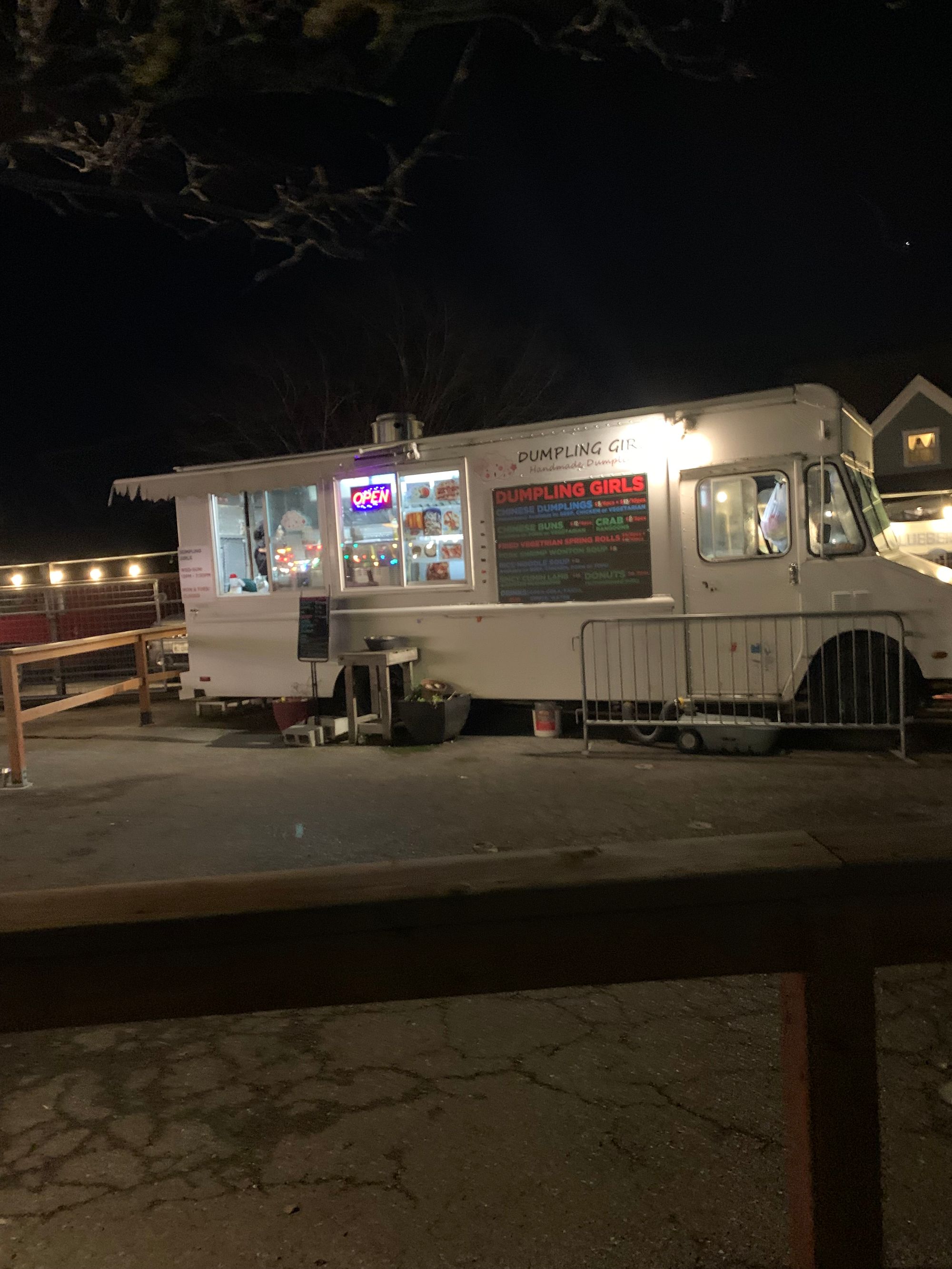 dark sky, white Dumpling Girls food truck with an open sign, painted menu